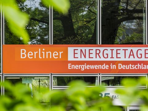 Banner der Berliner Energietage draußen, grüne Blätter im Vordergrund
