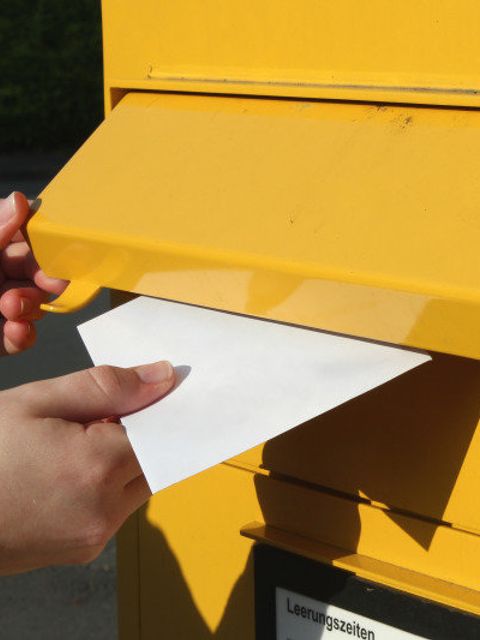 Brief wird in Briefkasten eingeworfen