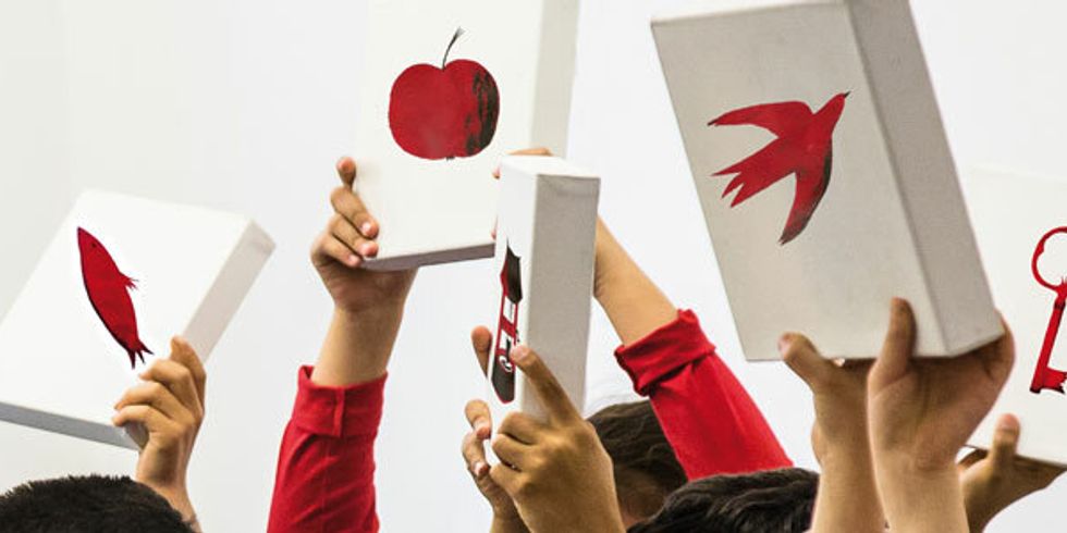 Kinderhände halten weiße Boxen mit roten Motiven in die Luft