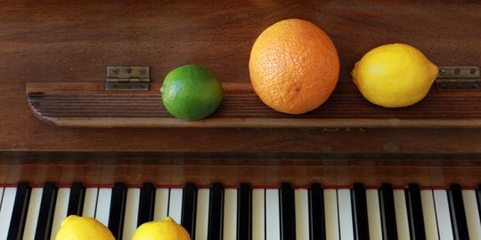 Tastatur eines Klaviers mit Zitrusfrüchten