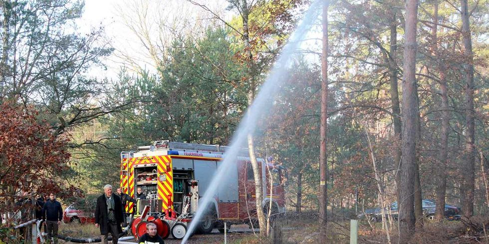 eine Feuerwehr steht im Wald und es wird ein Löschwasserbrunnen getestet