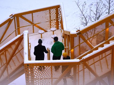 Bildvergrößerung: Drei Menschen laufen über eine gelbe Zick-Zack-Treppe im Schnee.
