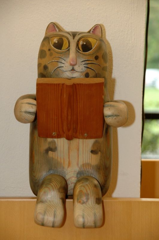 Katze aus Holz mit Buch in den Pfoten