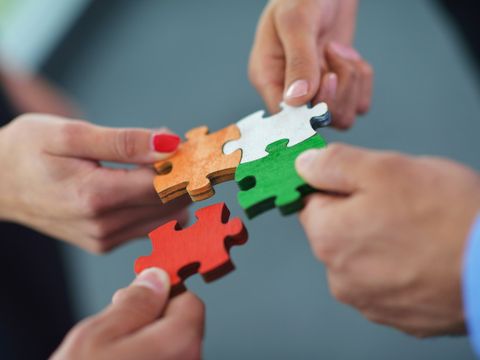 Hände stecken vier Puzzleteile zusammen
