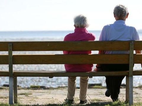 Älteres Paar auf einer Bank am Strand