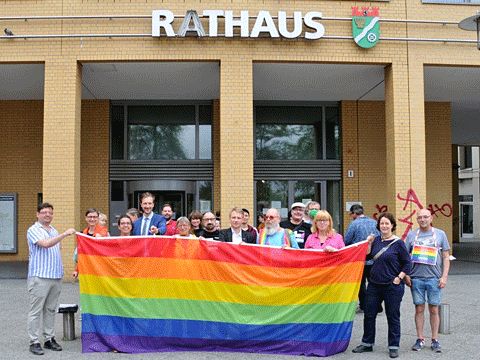 Hissen der Regenbogenfahne vor dem Rathaus 2021 - Die Teilnehmenden präsentieren die Fahne