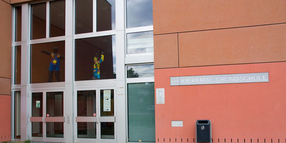 Der Eingang der Kiekemal Grundschule mit silbergrauem Schriftzug an der Wand