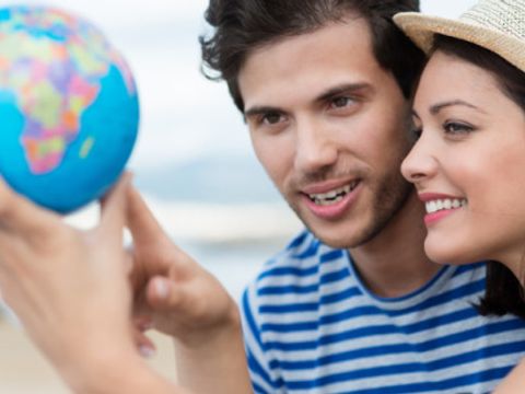 Ein junges Paar hält einen Globus in den Händen und zeigt darauf