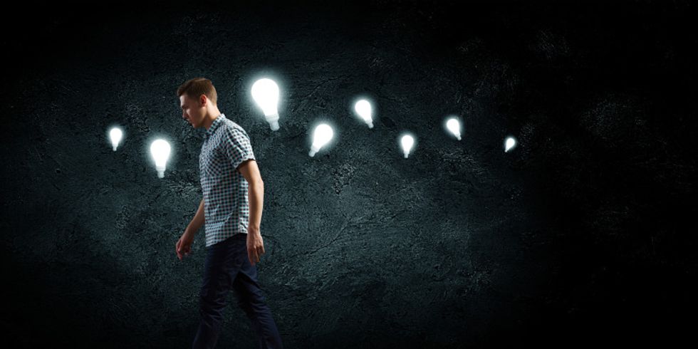 Laufender Mann vor dunklem Hintergrund mit mehreren Glühbirnen