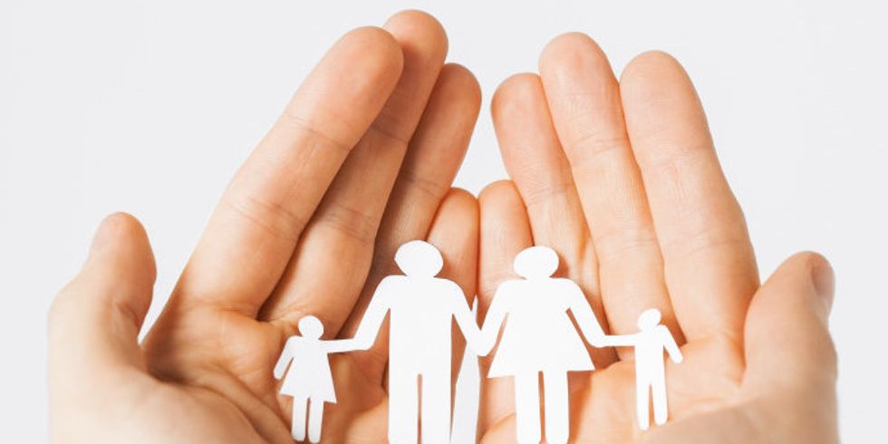 Bildausschnitt: Hände halten schützend Scherenschnitt von einer Familie