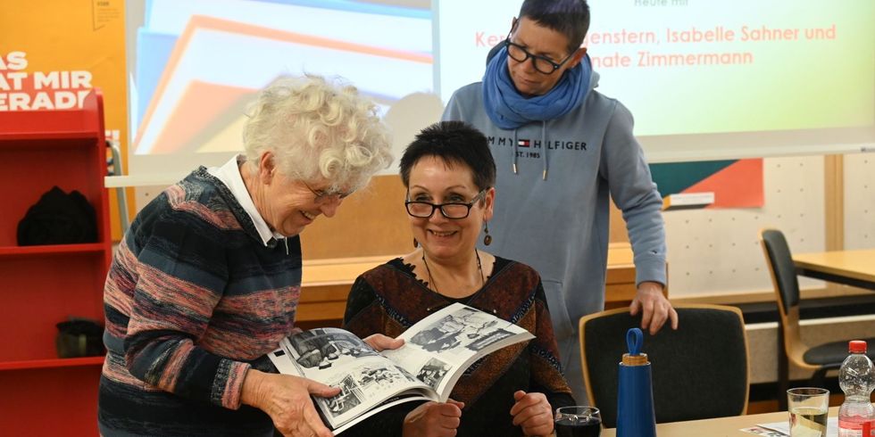 Reihe "Schwebende Bücher" Das Foto zeigt Bibliothekarinnen im Gespräch mit einer Besucherin. 