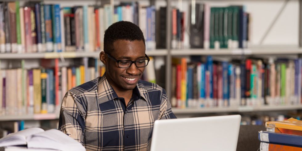 Student an seinem Laptop in der Bibliothek