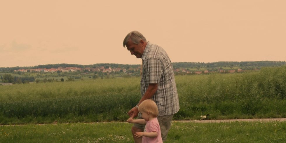 Opa mit seinem Enkelkind auf einer Wiese