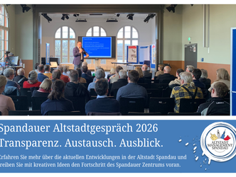 Vortragender steht vor Publikum in hellem Saal mit großen Fenstern und präsentiert vor blauem Bildschirm mit Text