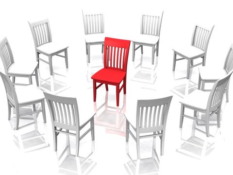 Weiße Stühle im Kreis mittig mit einem roten Stuhl