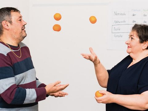 Frau und Mann beim Suppe kochen mit Orangen jonglierend