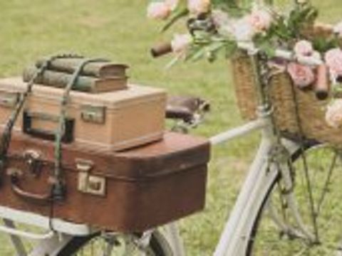 Oldtimer-Fahrrad beladen mit Koffern und einem Korb mit Blumen an der lenkstange