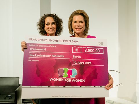 Nancy Brincker und Muna Naddaf halten den Scheck für den Frauengesundheitspreis-Gewinner in den Händen.