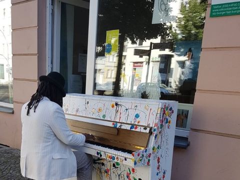 POC spielt Klavier auf der Straße vor dem Nachbarschaftszentrum Brunnentreff