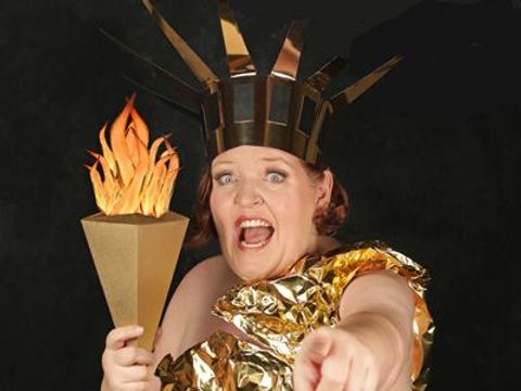 Helene Mierscheid - Golden Girl für alle Fälle. Helene Mierscheid in einem Kostüm aus goldener Folie, das die amreikansiche Freiheitsstatue mit Fackel und Strahlenkrone darstellt.