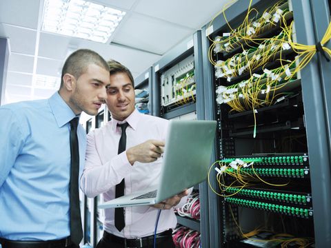 Zwei Männer mit Laptop vor Serverschrank