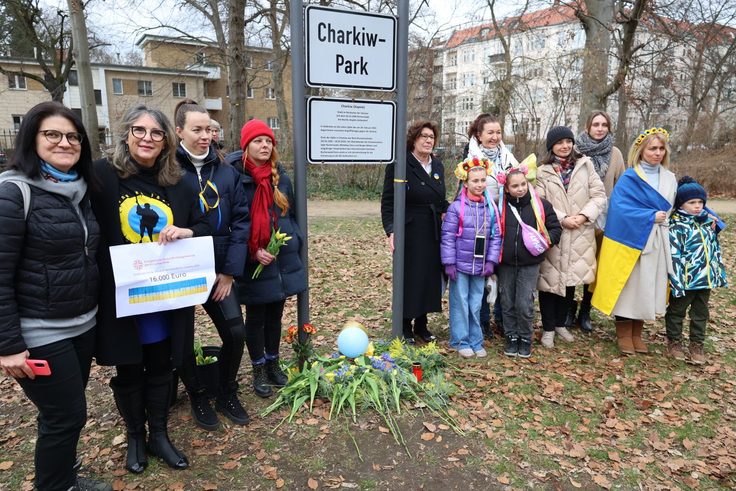 24. Februar 2024: Bezirksbürgermeisterin Schellenberg (rechts neben dem Schild) mit Mitgliedern der ukrainischen Community. Olga Pischel (2.v.l.) zeigt 16.000-Euro-Spende der ev. Pauluskirchengemeinde Lichterfelde. 