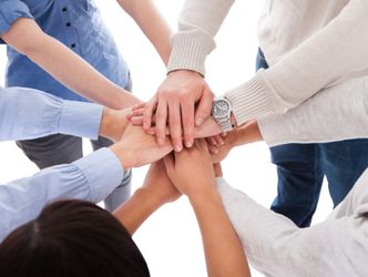 Eine Gruppe von Menschern legt ihre Hände kreisförmig übereinander