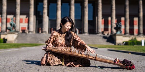 Musikerin Hyunjeong Park spielt Gayageum vor dem Alten Museum in Berlin