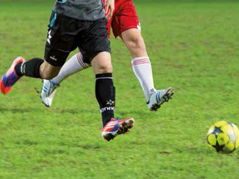 Beine von Fußballspielern mit Ball auf dem Fußballfeld