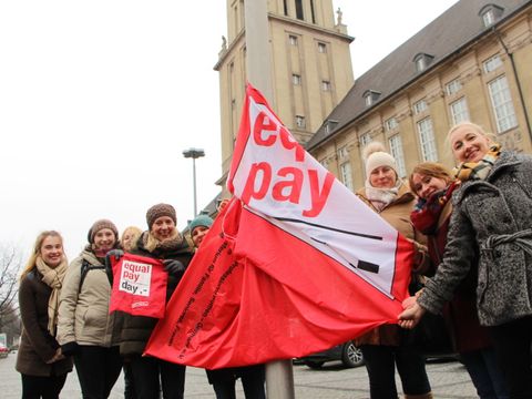 Bildvergrößerung: Frauen halten gemeinsam die Equal-Pay-Day-Fahne.