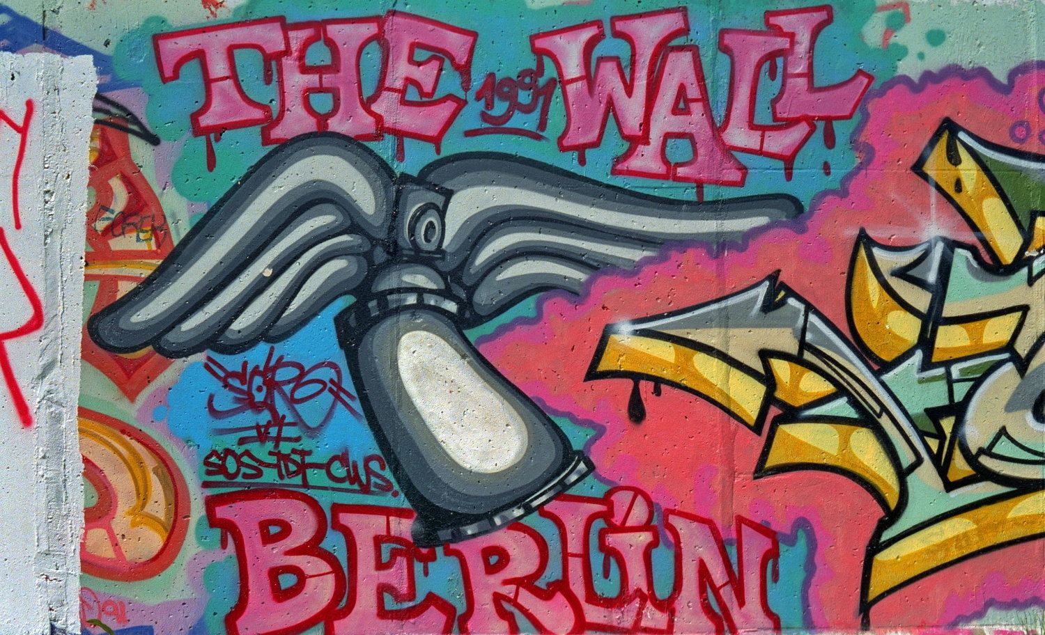 eine bunt besprühte Betonwand mit der Aufschrift The Wall Berlin