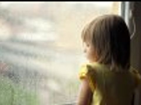 Kind stehend am verregnetem Fenster