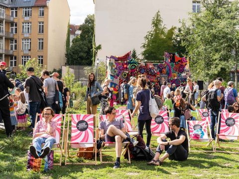 Menschen auf Liegestühlen und stehend beim Sommerfest im Garten der Stadtbibliothek