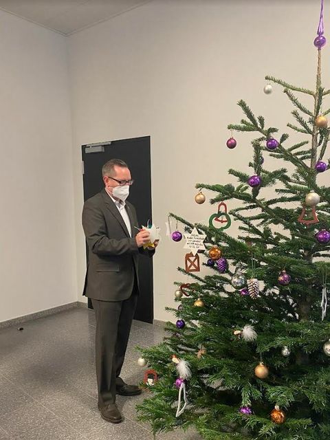 Bildvergrößerung: Bezirksbürgermeister Igel schmückt den Wunschbaum im Allianz Gebäude 2022