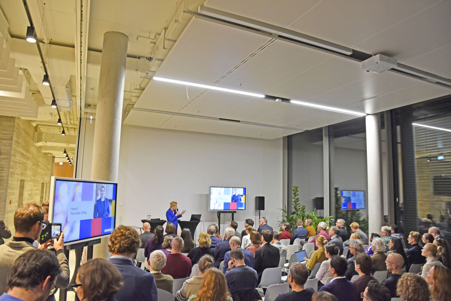 Blick über Köpfe hinweg auf eine Bühne mit Redner