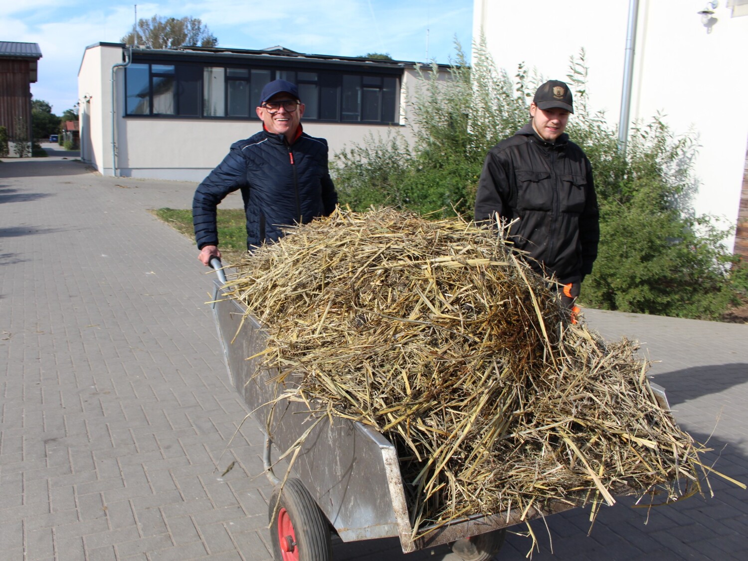 Herr Reinhofer schiebt Schubkarre unter Anleitung von Maurice