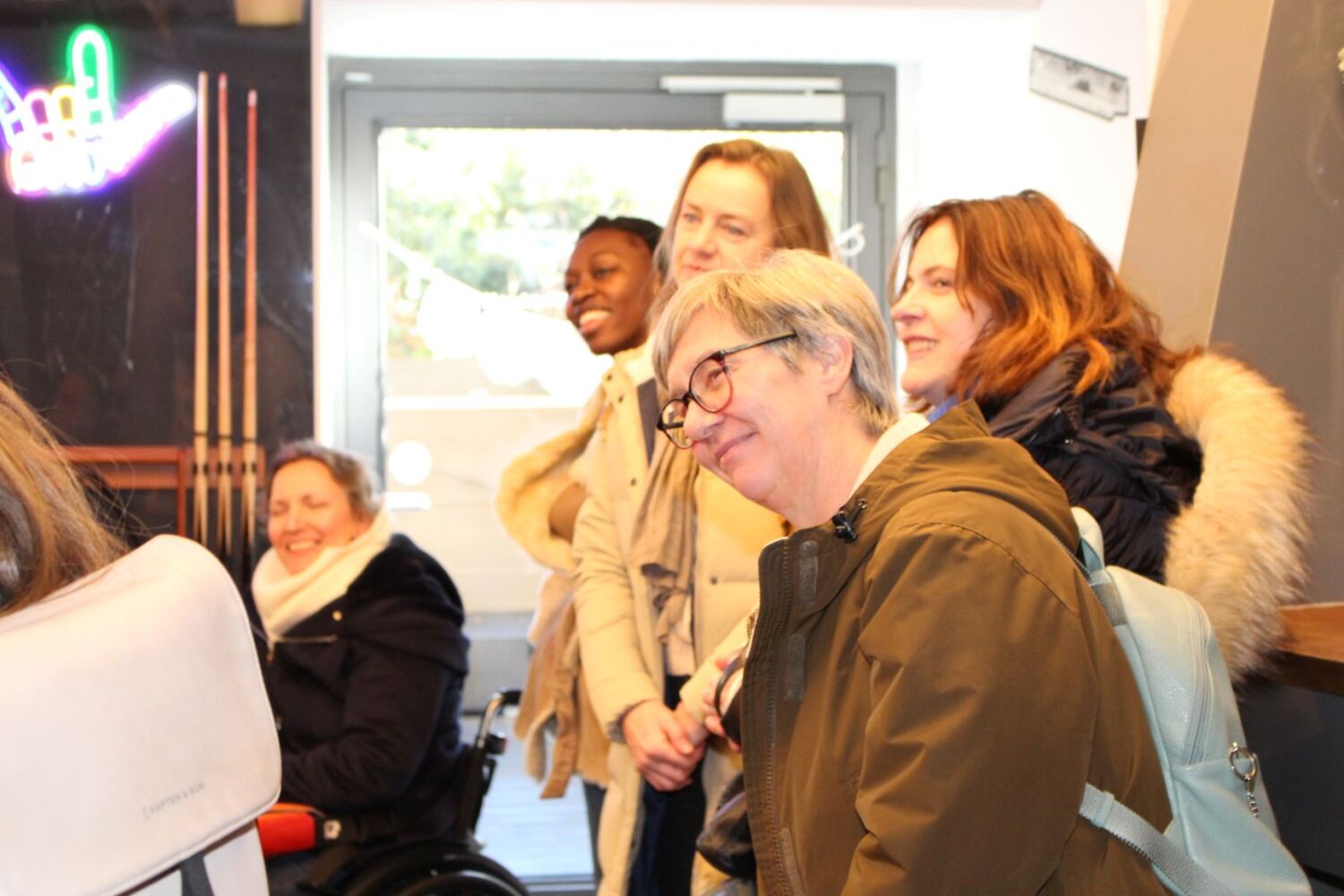 Eine Gruppe von fünf freundliche lachenden Frauen stehen im Halbkreis und blicken in eine Richtung.