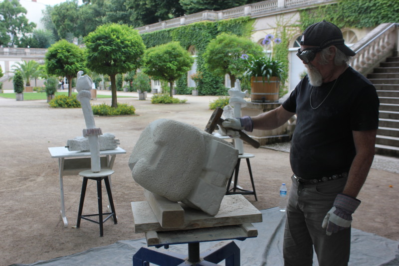 Der Bildhauer Johann Behrends bei der Bearbeitung eines Steines. Im Hintergrund die Galerie im Körnerpark.