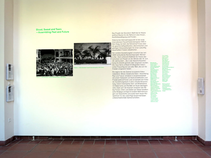 Eingangswand der Galerie mit einem einführenden Text und zwei historischen Fotos zum Thema der Ausstellung