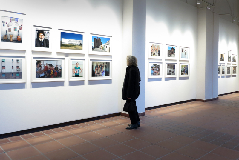 In drei Nischen sieht man die in zwei Reihen übereinander angeordneten Fotoarbeiten. Im Vordergrund steht eine Besucherin und betrachtet die Aufnahmen eingehend.