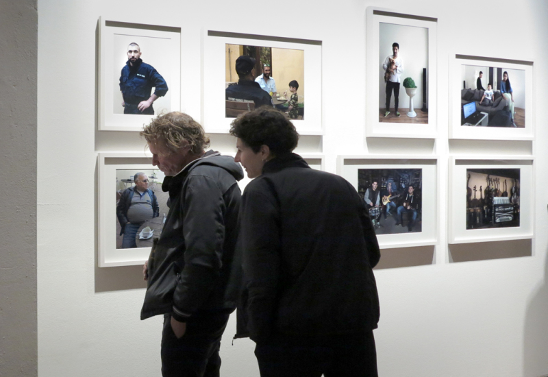 Vor der Fotoserie "Brno" stehen zwei Besucher und lesen den Informationstext. Die Serie zeigt verschiedene Männer im Kontext ihrer Arbeit als Musiker und in Uniform in Ihrer Funktion als Präventiv-Polizeieinheit, sowie im Kontext ihrer Familien.