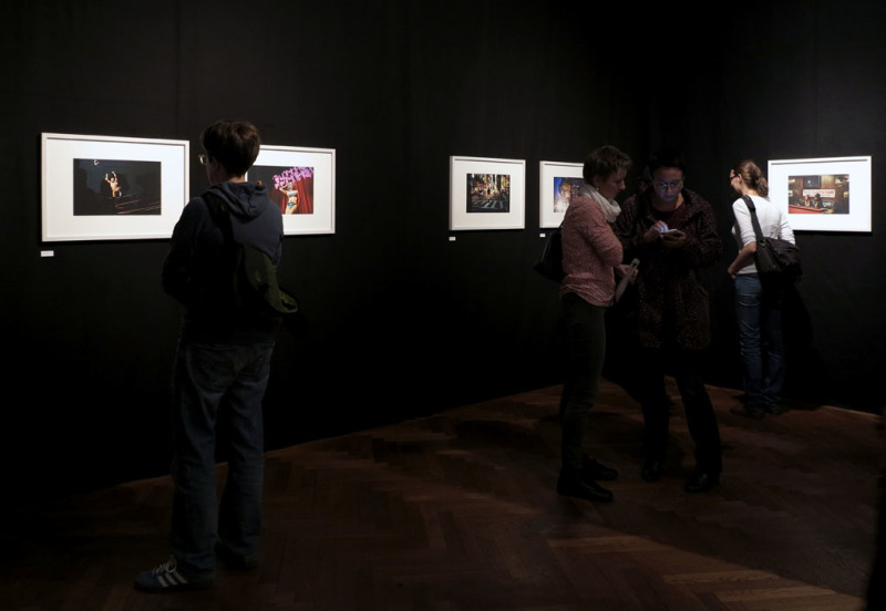 Blick in die Ausstellung mit einer Fotoserie auf schwarzen Wänden