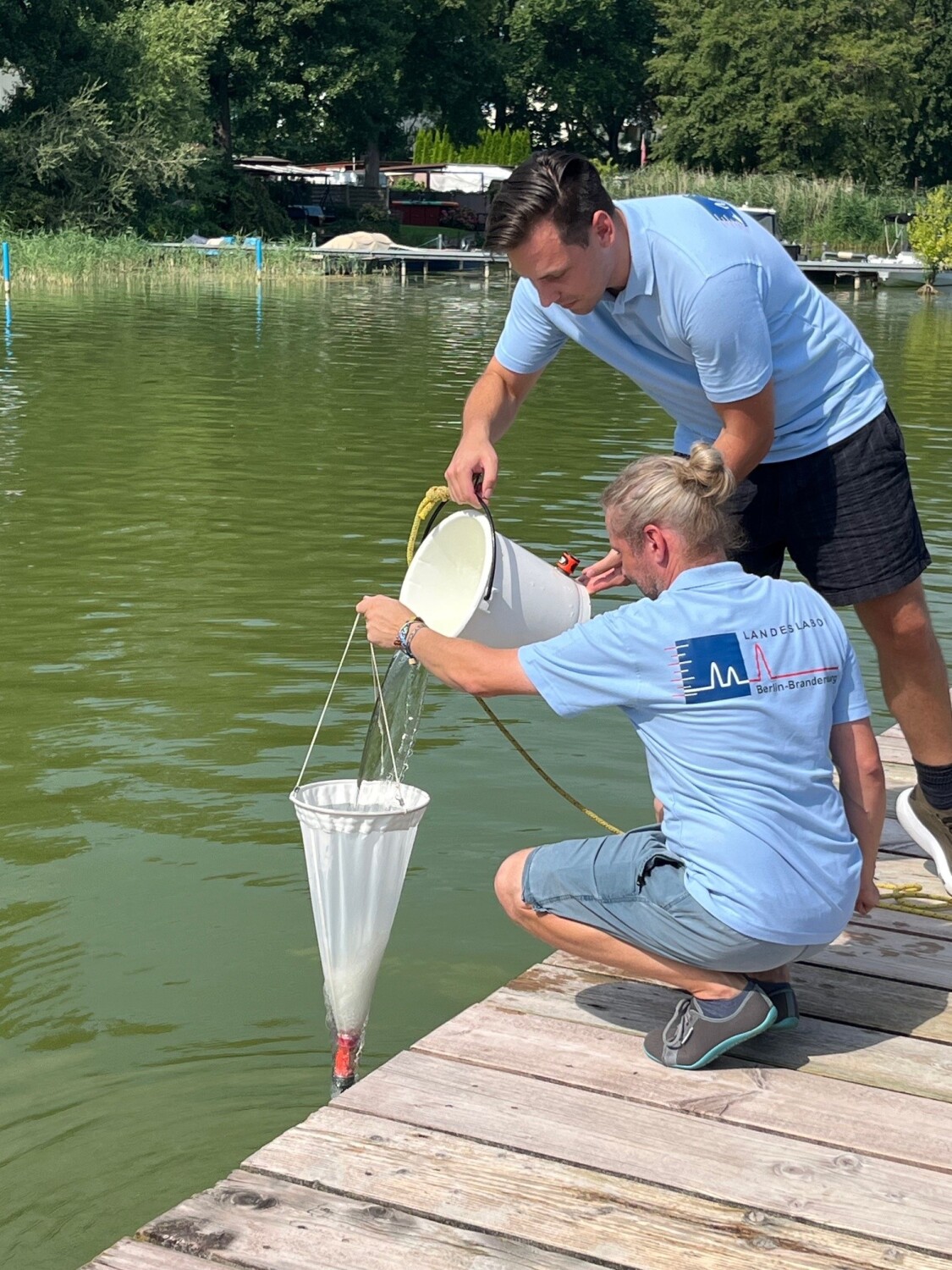 Zwei Mitarbeiter des Landeslabors nehmen Wasserproben an einer Berliner Badestelle