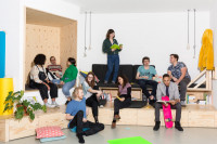 10 junge Menschen tauschen sich in unterschiedlichen Kleingruppen in einem hellen, modernen Raum aus.