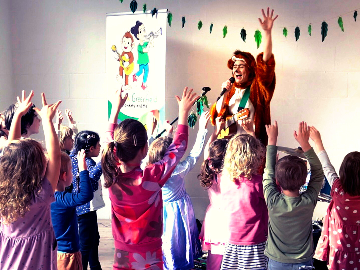 Kinder tanzen mit einer Frau in einem Plüschkostüim
