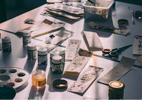 Blick auf einen Tisch mit verschiendenen Malutensilien und Scheren