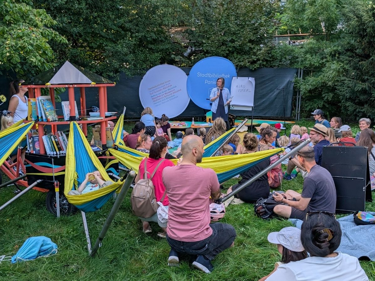 Menschen bei einer Lesung draußen auf der Wiese