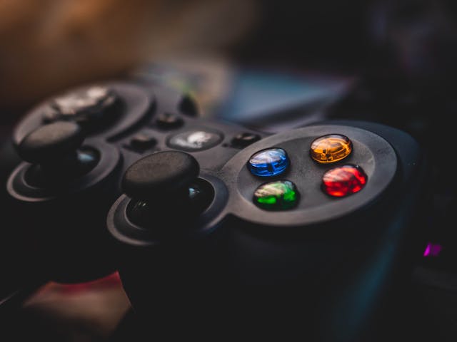 Zwei Personen spielen in der Gaming-Ecker des Makerspaces ein Spiel mit Controllern auf einem großen Bildschirm
