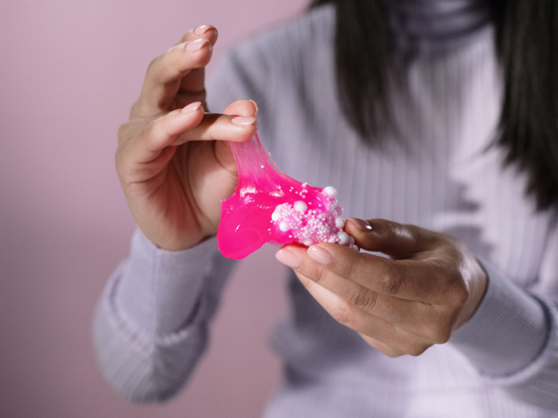 Eine Person hält pinken Schleim mit Kugeln in der Hand