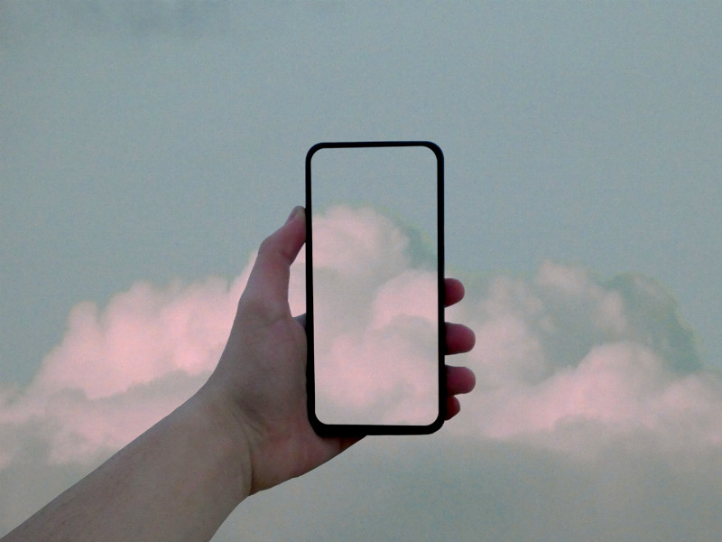 Eine Hand mit Handy, auf dem eine Bild-App auf dem Display das Himmelsbild vervollständigt.